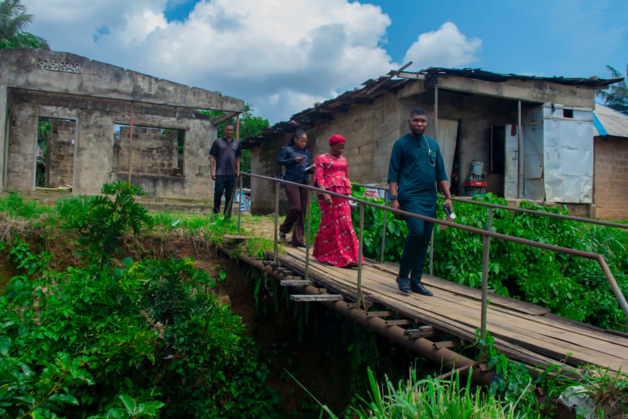 Comrade Ini-obong Uko and the team crossing a makeshift bridge in an affected community
